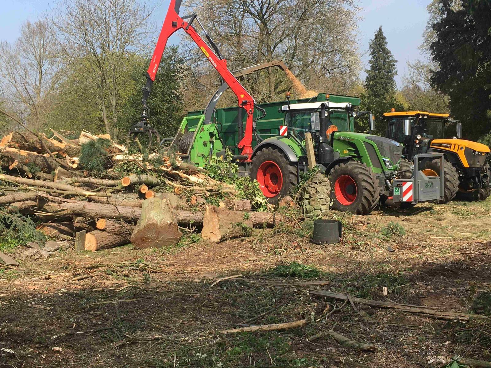 Tractor, chipper crane and log pile on a large clearance site