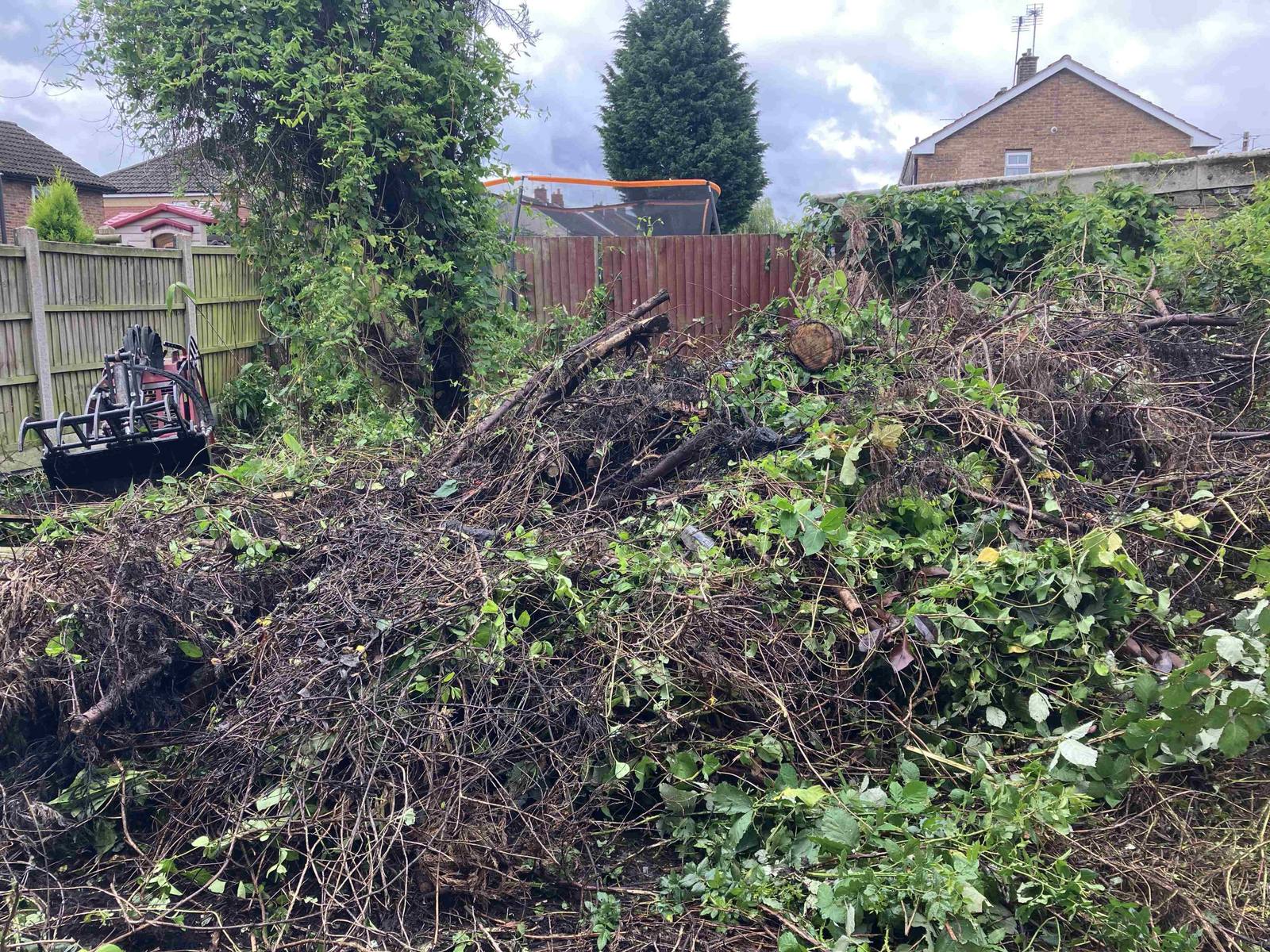 Garden clearance with debris pile and tracked equipment